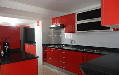 Muebles de cocina con puertas color rojo rubi, cubierta de granito negro San Gabriel instalado en Puente Alto
